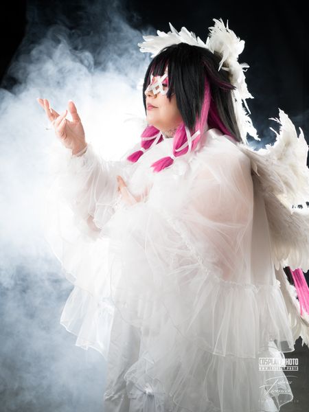 Cosplay féminin en robe blanche tulle et plumes, masque ailé sous fumée blanche — Fabrice Fiorucci Photographe