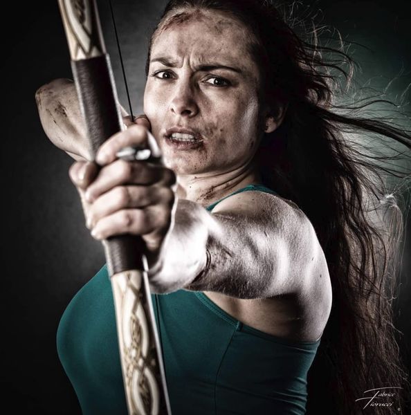 Cosplay Lara Croft (Tomb Raider), portrait à l'arc tendu, visage marqué de boue — Fabrice Fiorucci Photographe
